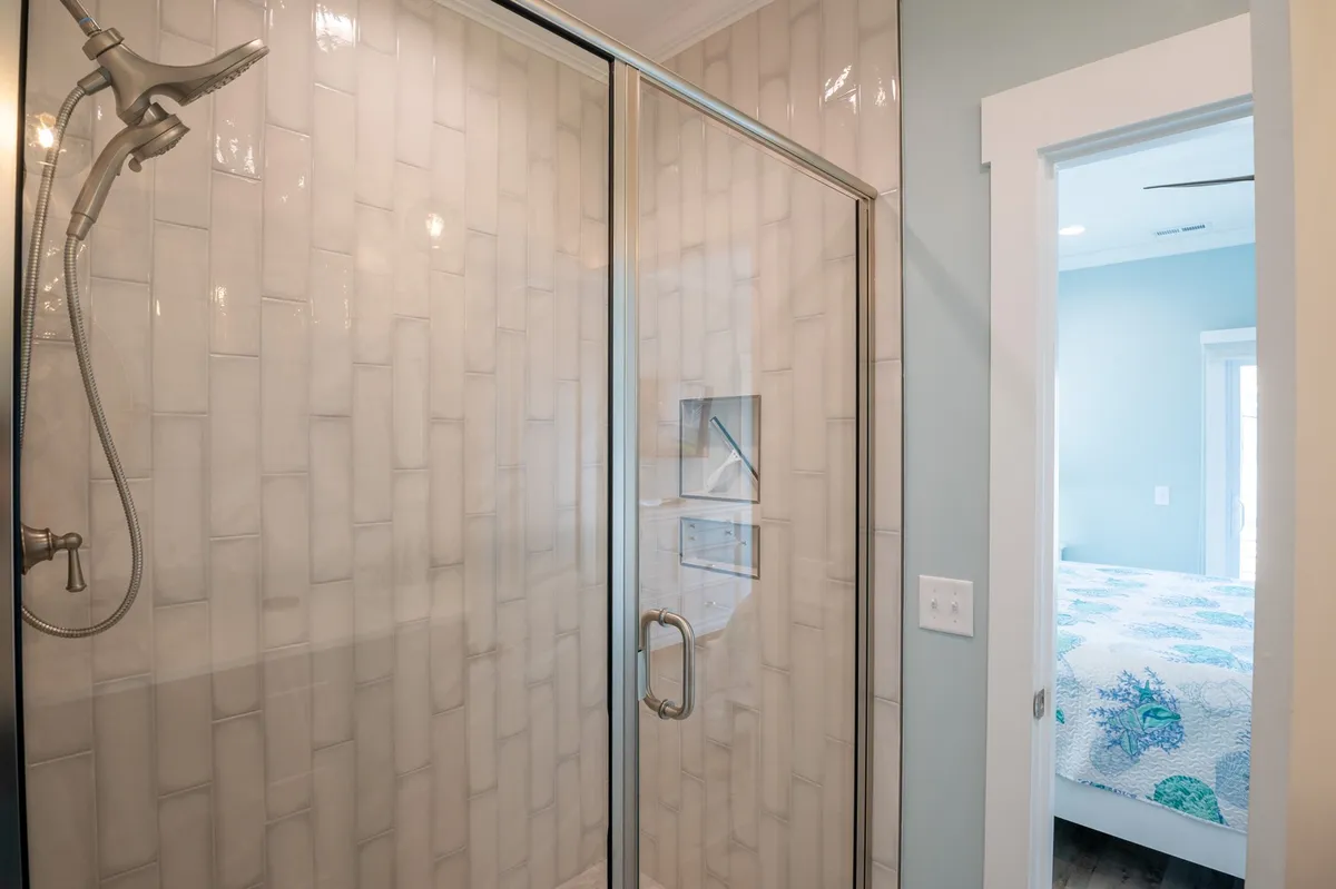 A modern bathroom interior featuring a glass-enclosed shower, textured tile walls, and a sleek shower head, creating an atmosphere of relaxation and high-end design.