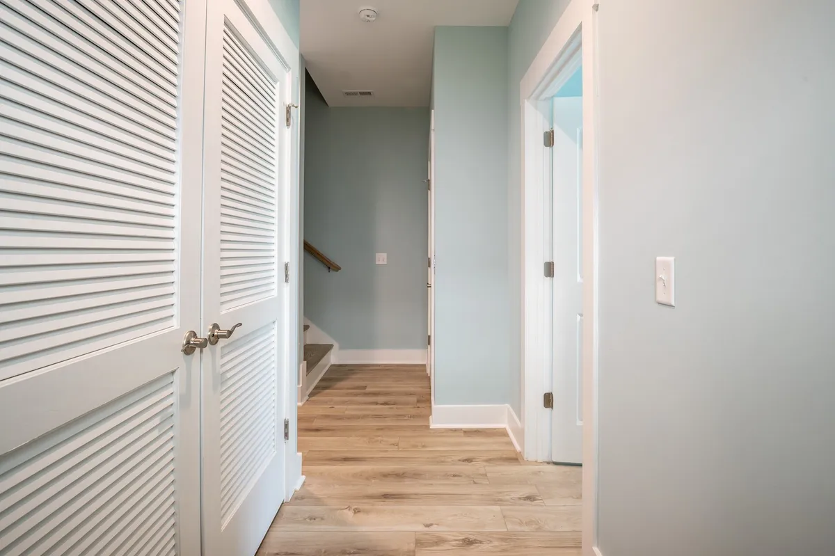 A welcoming interior view with white louvered doors, light blue walls, and a staircase leading to private rooms, suggesting a smooth, uncluttered flow throughout the home.