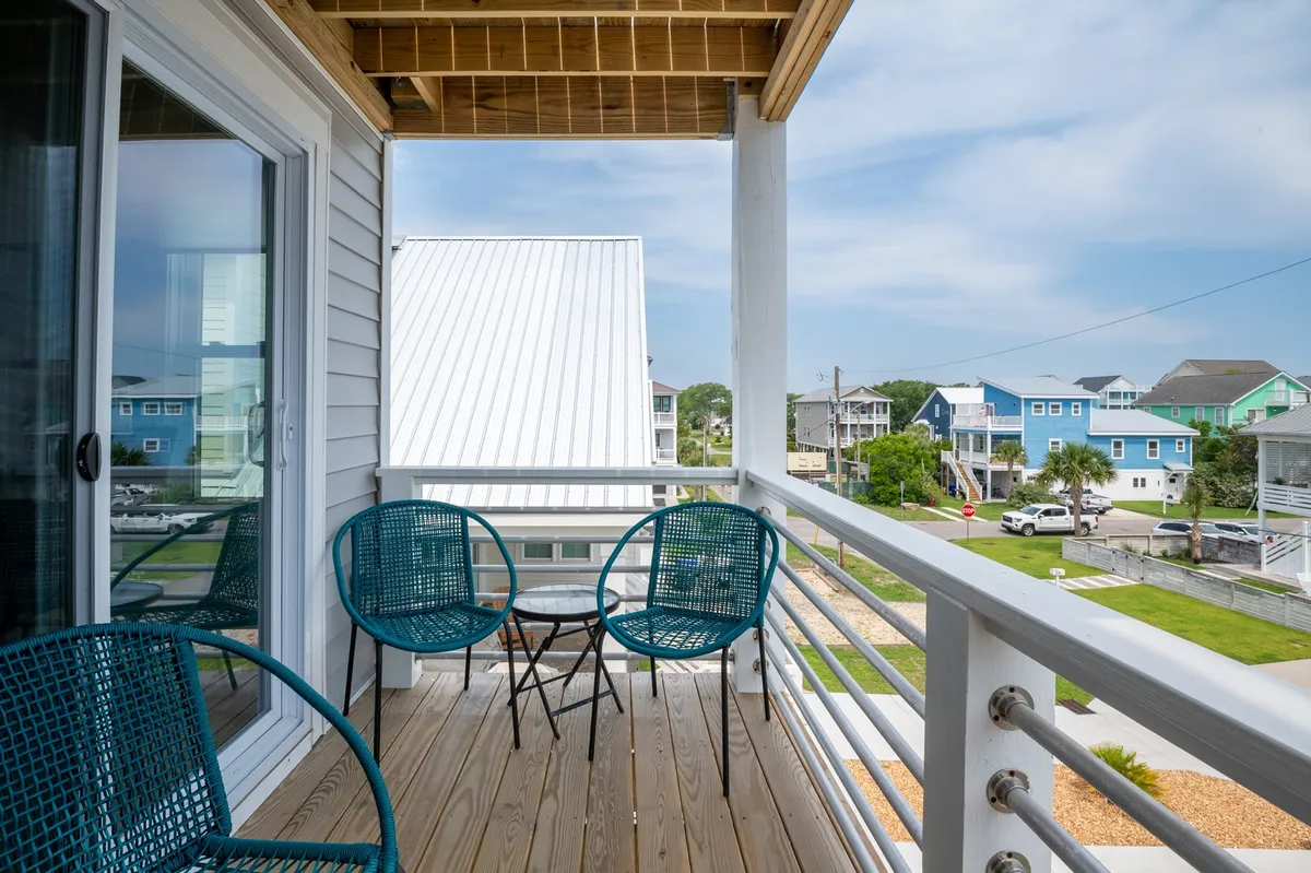 A peaceful wooden deck with outdoor chairs, offering a panoramic view of the surrounding neighborhood and distant rooftops. The scene invites guests to unwind, socialize, and take in sunset views or the fresh sea air, embodying the blend of privacy and openness.