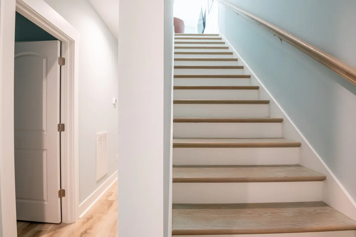 This image shows a bright staircase and open doorway, offering a sense of movement, transition, and anticipation. The open, airy feel suggests the freedom to explore both within the home and in the surrounding area.