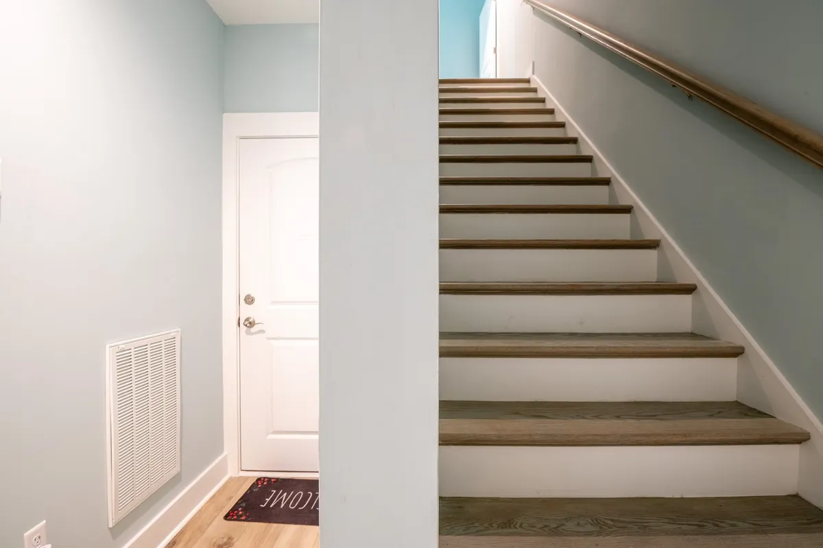 This image captures the home's entryway, featuring a staircase, a front door, and a welcoming mat. The scene evokes the warmth and anticipation of arriving at a vacation destination, with light streaming in and hints of the home's inviting atmosphere beyond.